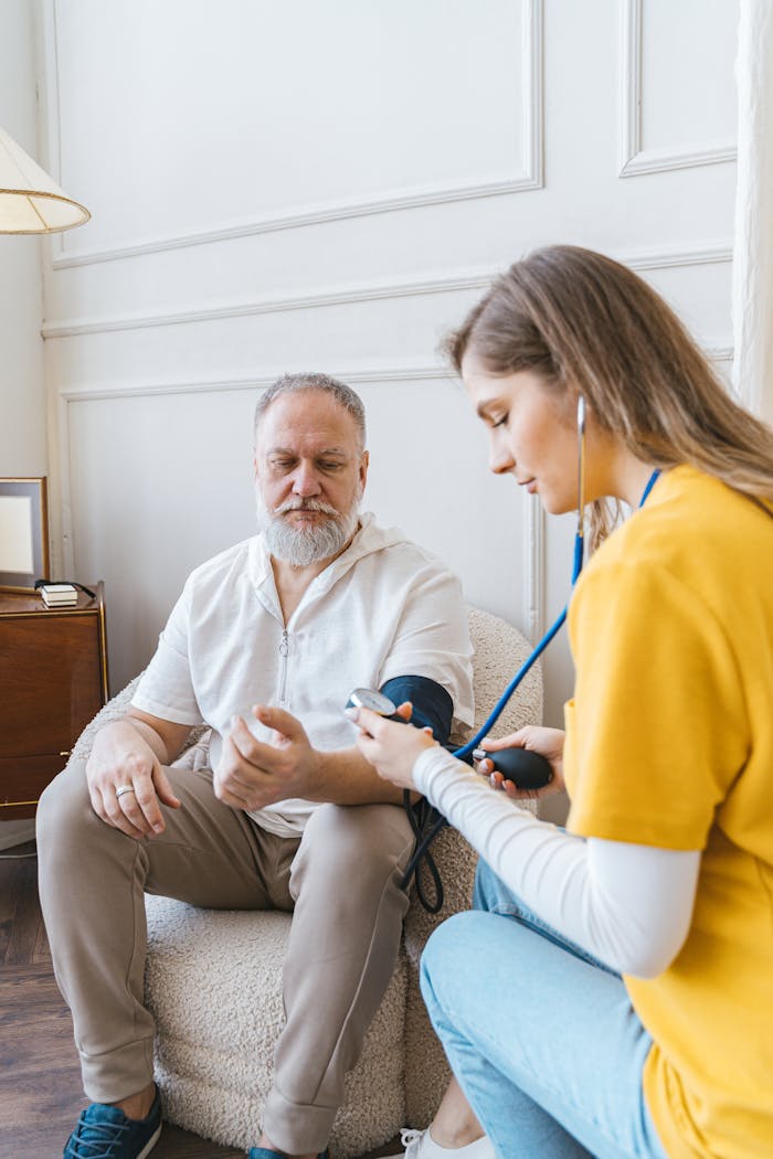 A healthcare professional checks an elderly man's blood pressure in a cozy room.